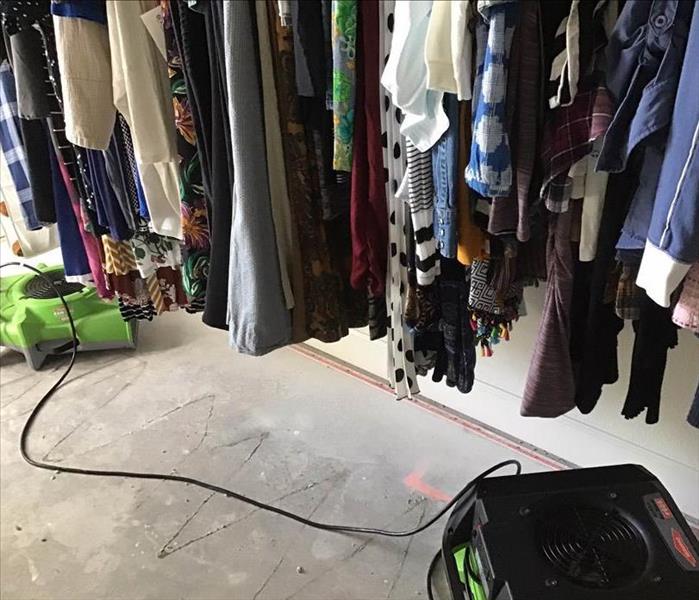 closet with clothes and drying equipment on the floor